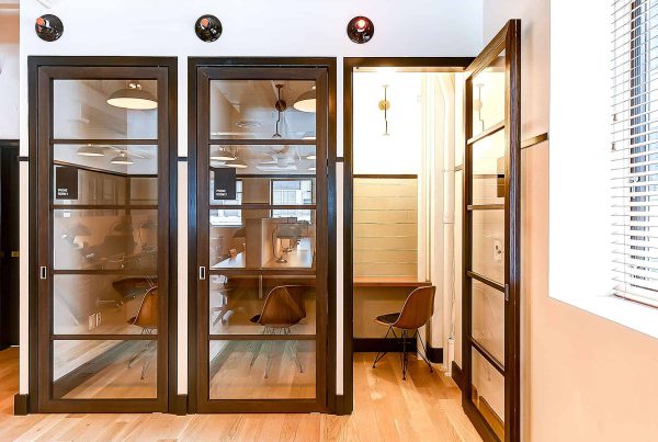 View of sleek phone rooms featuring dark-framed glass doors, providing privacy while allowing natural light to permeate the workspace. A mix of functionality and modern design enhances the office environment.