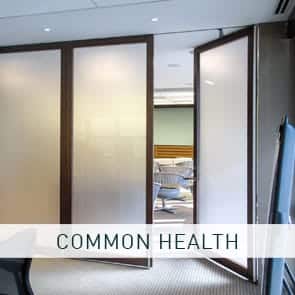 A stacking wall system featuring frosted paneling opens to reveal a classroom-like setting next to a conference room