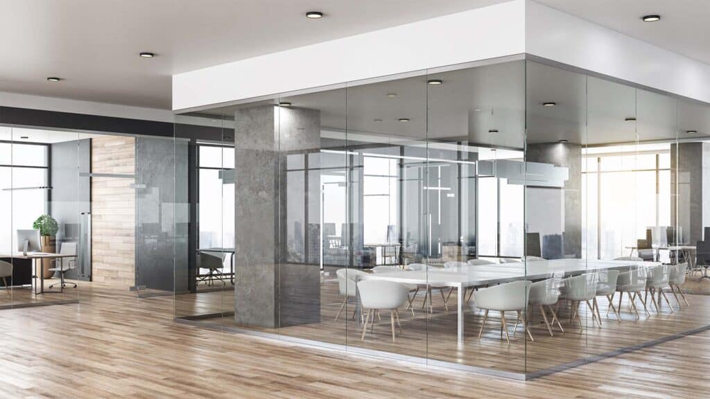An office with wood floors and glass walls surrounding a conference room.